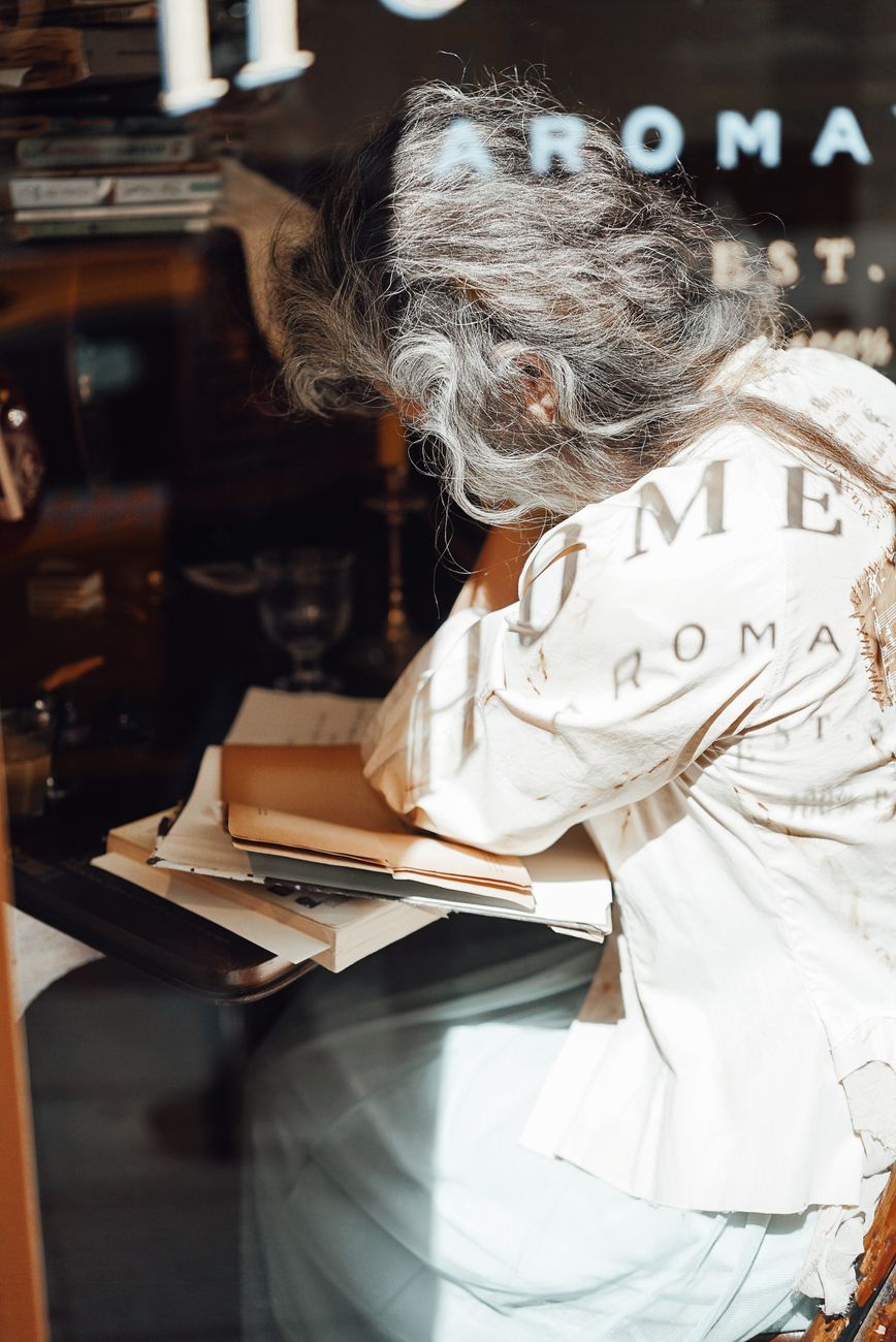 Author reading travel logs at rustic wooden desk by sunlit window